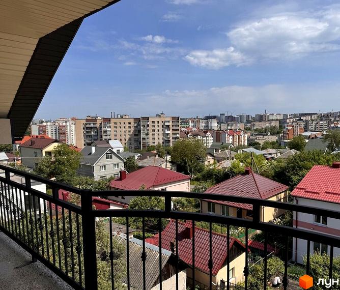 Вид з балкона на житловий комплекс на вулиці Безкоровайного, 5. Навколо багатоповерхові будинки та приватні садиби з червоними дахами.