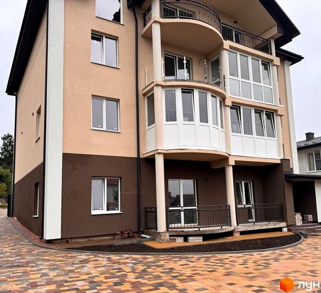 Фасад новобудови на вул. Безкоровайного, 5, з балконами та великими вікнами. Територія перед будинком вимощена плиткою.