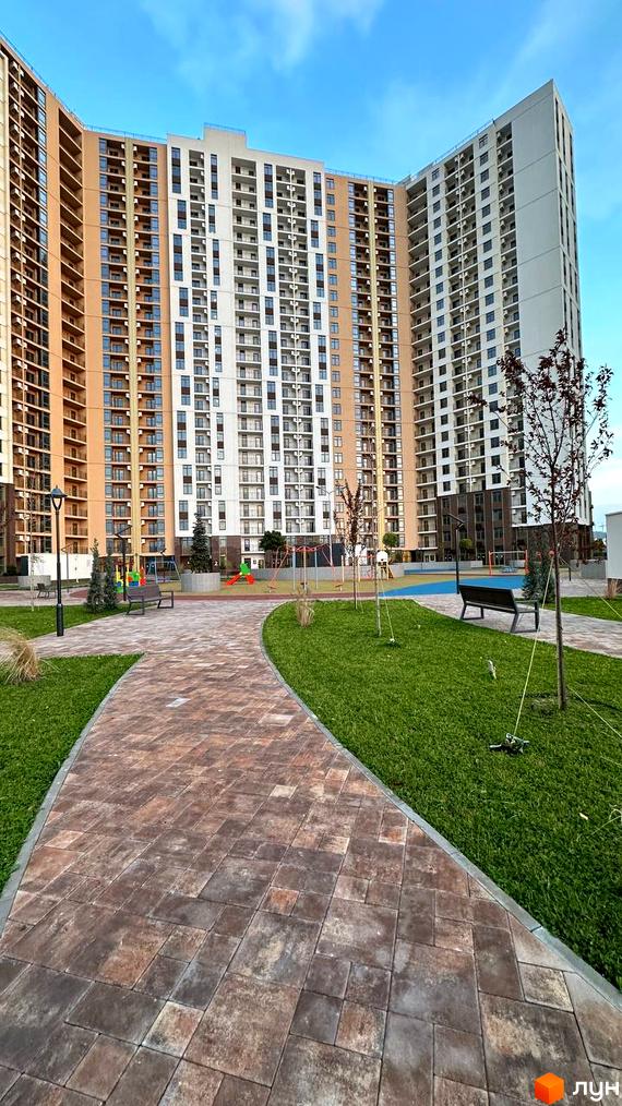 Житловий комплекс KADORR City з білою та бежевою фасадною частиною та дитячим майданчиком на прибудинковій території.