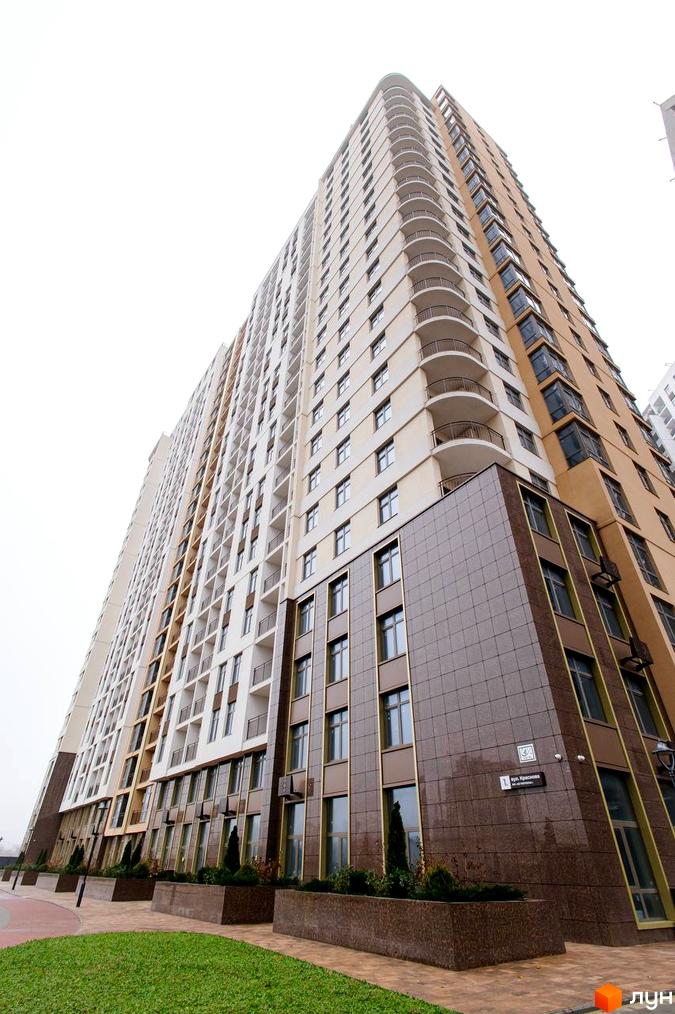 Високоповерховий житловий комплекс KADORR City з балконами та великими вікнами, з доглянутою прибудинковою територією та зеленими насадженнями.