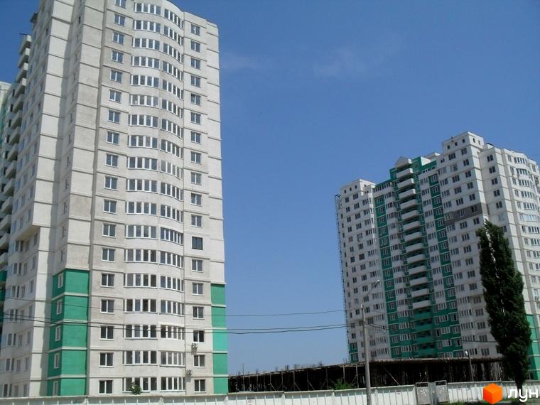 Житловий комплекс Європейський з двома багатоповерховими будинками та прибудинковою територією. На фоні ясне небо та зелені насадження.