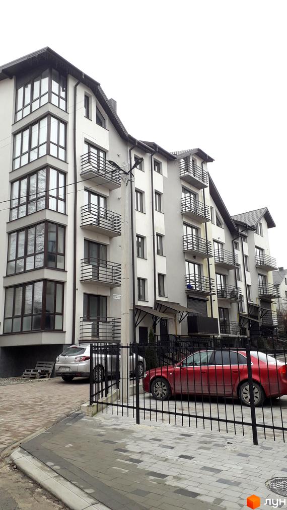 Зовнішній вигляд житлового комплексу на вулиці Квітки Цісик, 54а, б, в, г з автомобілями на прибудинковій території.