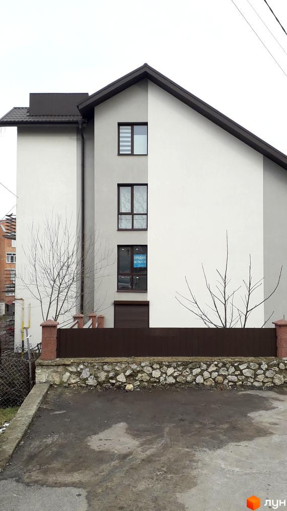 Зовнішній вигляд новобудови на вул. Квітки Цісик, 54а, б, в, г. Навколо будинку розташована прибудинкова територія з парканом та деревами.