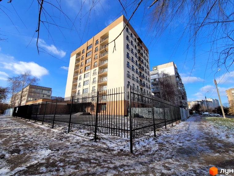 Житловий комплекс Темп - багатоповерховий будинок з балконами та чорним парканом на тлі блакитного неба. Навколо будівлі засніжена територія.