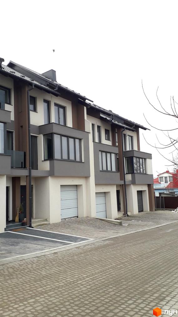 Зовнішній вигляд триповерхових будинків з гаражами та балконами на вулиці Квітки Цісик, 31. Прибудинкова територія вимощена бруківкою.