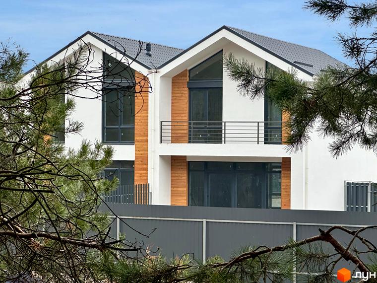 Сучасні дуплекси WoodSky з дерев'яними елементами фасаду та великими вікнами. Навколо будівель видно зелені дерева та паркан.