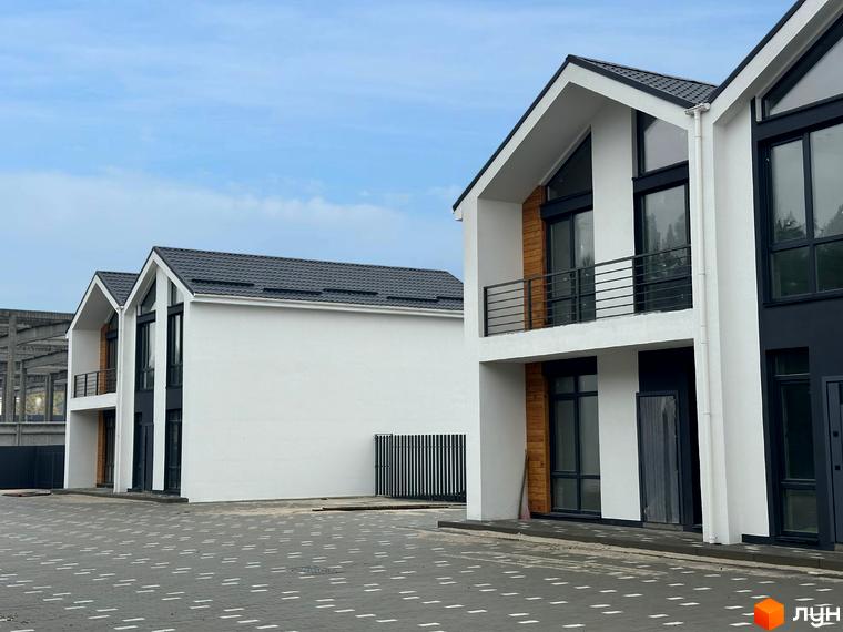 Дуплекси WoodSky - двоповерхові будинки з білими фасадами, темними вікнами та балконами. Навколо будівель розташований вимощений сірою плиткою двір.