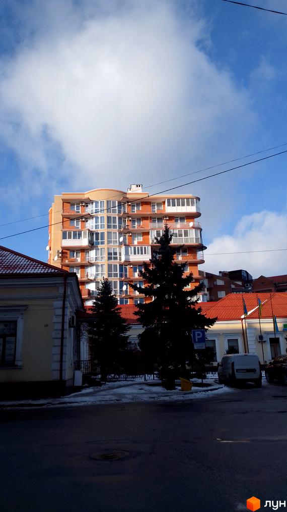 Сучасна новобудова на вулиці Родини Барвінських, 2 з великою кількістю вікон та балконів. Навколо будинку розташовані дерева та прибудинкова територія.