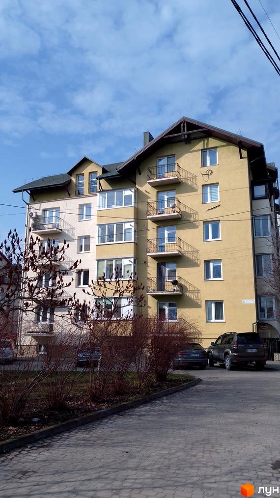 Зовнішній вигляд житлового комплексу на вул. Новий Світ, 17а, з балконами та вікнами. На прибудинковій території видно паркування з автомобілями та зелені насадження.