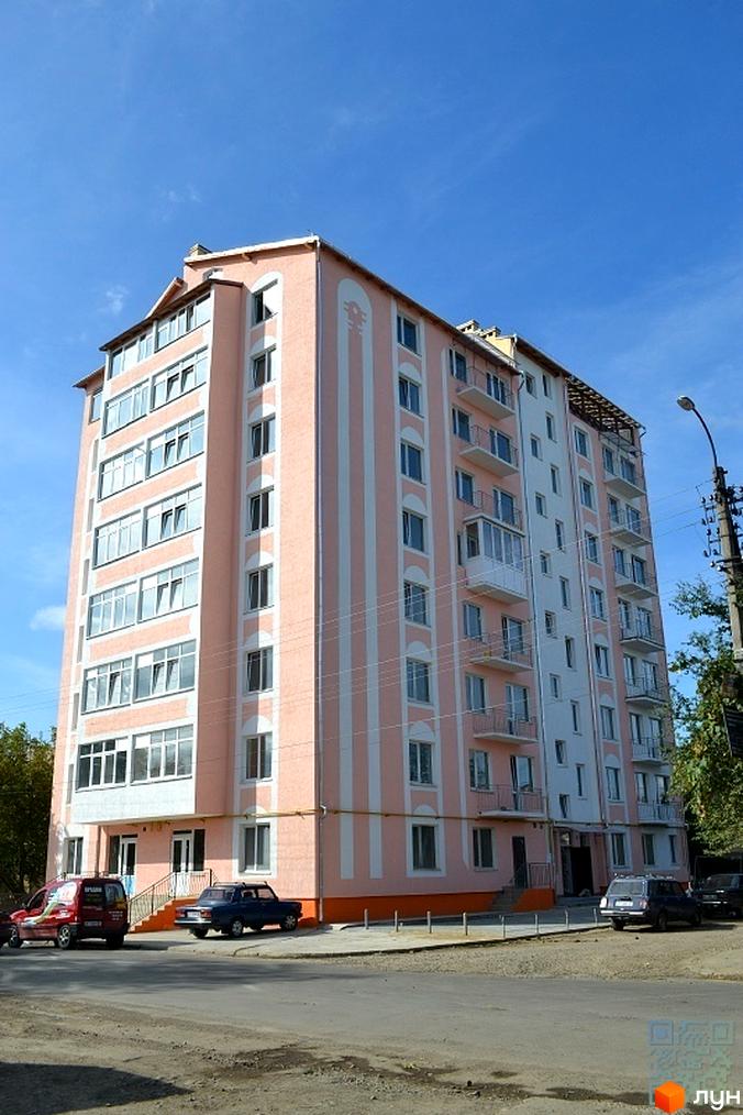 Фото фасаду дев'ятиповерхового будинку по вулиці Ленкавського, 28а. Перед будинком видно дорогу та припарковані автомобілі.