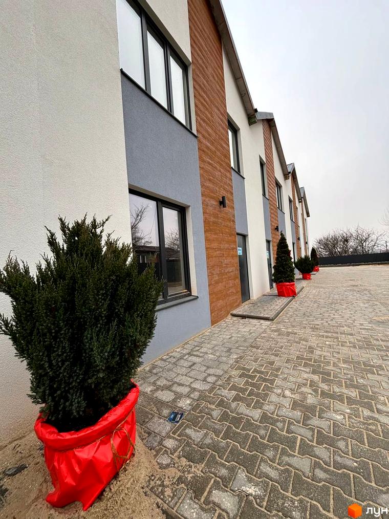 Таунхауси Klever House з сірими та дерев'яними фасадами, вікнами та бруківкою на прибудинковій території.