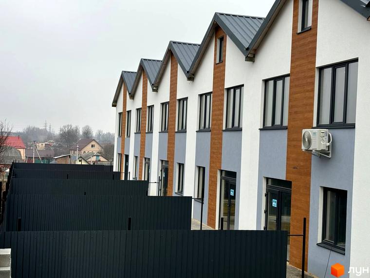 Зовнішній вигляд таунхаусів Klever House з сірим дахом та дерев'яними вставками, на тлі видно паркан та інші будинки.