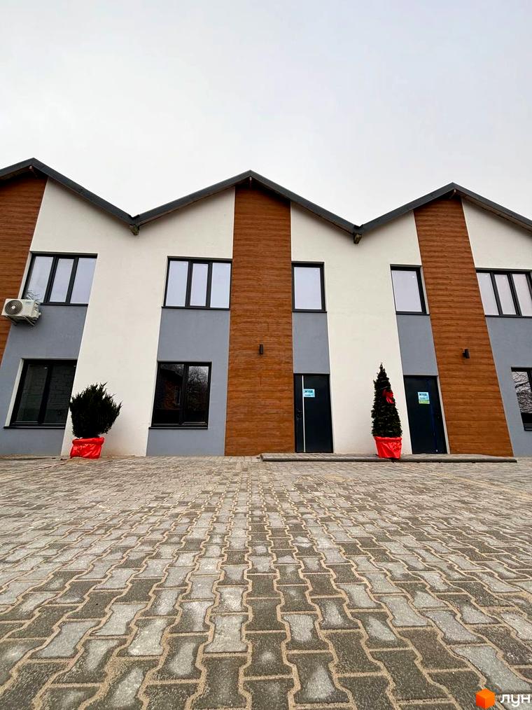 Зовнішній вигляд таунхаусів Klever House з дерев'яними та сірими елементами фасаду та бруківкою перед будинком. Зовнішній вигляд таунхаусів Klever House.