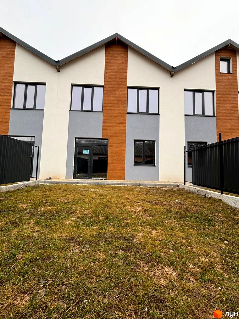 Зовнішній вигляд таунхаусів Klever House з дерев'яними та сірими фасадами, вікнами та прибудинковою територією з травою та парканом.