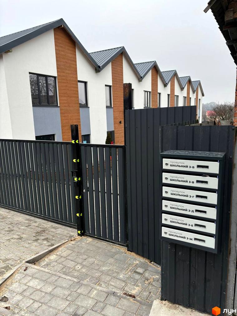 Зовнішній вигляд таунхаусів Klever House з сірими дахами та білими стінами, прибудинкова територія з огорожею та поштовими скриньками.