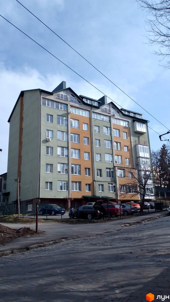 Зовнішній вигляд новобудови на вулиці Вояків Дивізії Галичина, 26, з автомобілями на парковці перед будинком.