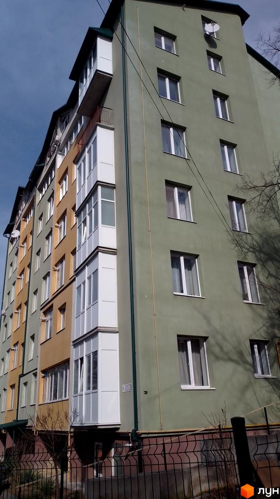 Фасад житлового комплексу на вулиці Вояків Дивізії Галичина, 26, з балконами та вікнами. Перед будинком видно паркан та дерева.