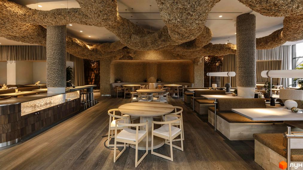 Інтер'єр ресторану з дерев'яними столами та стільцями, оздобленням з натуральних матеріалів та незвичайними стельовими конструкціями.