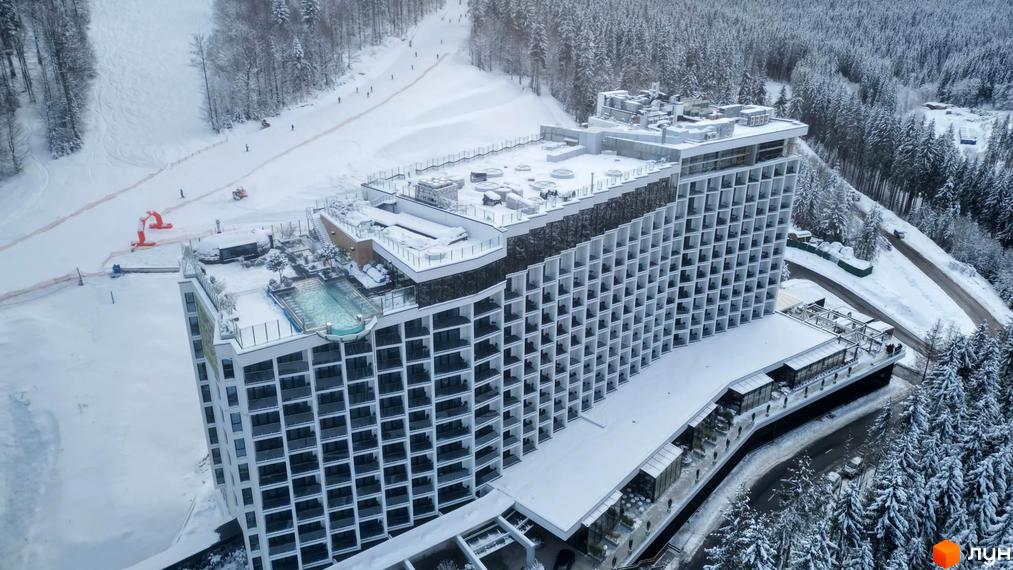 Апарт-комплекс Mountain Residence з басейном на даху в оточенні засніжених дерев. На схилі поруч видно лижну трасу з людьми.