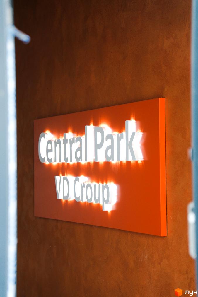 Підсвічений логотип ЖК Central Park на помаранчевій панелі, розташований на коричневій стіні. Вивіска з назвою житлового комплексу.