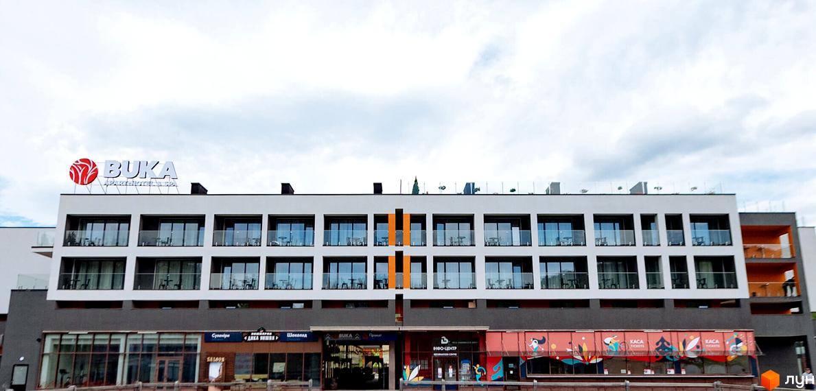 BUKA Apart-Hotel - це житловий комплекс з балконами та панорамними вікнами. Фасад будівлі оздоблений в сірих та помаранчевих тонах.