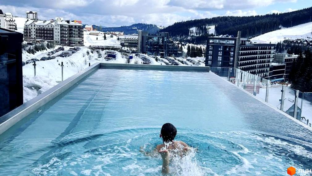BUKA Apart-Hotel: вид на житловий комплекс з басейном на фоні гір та снігу. Сучасна архітектура та зимовий відпочинок.