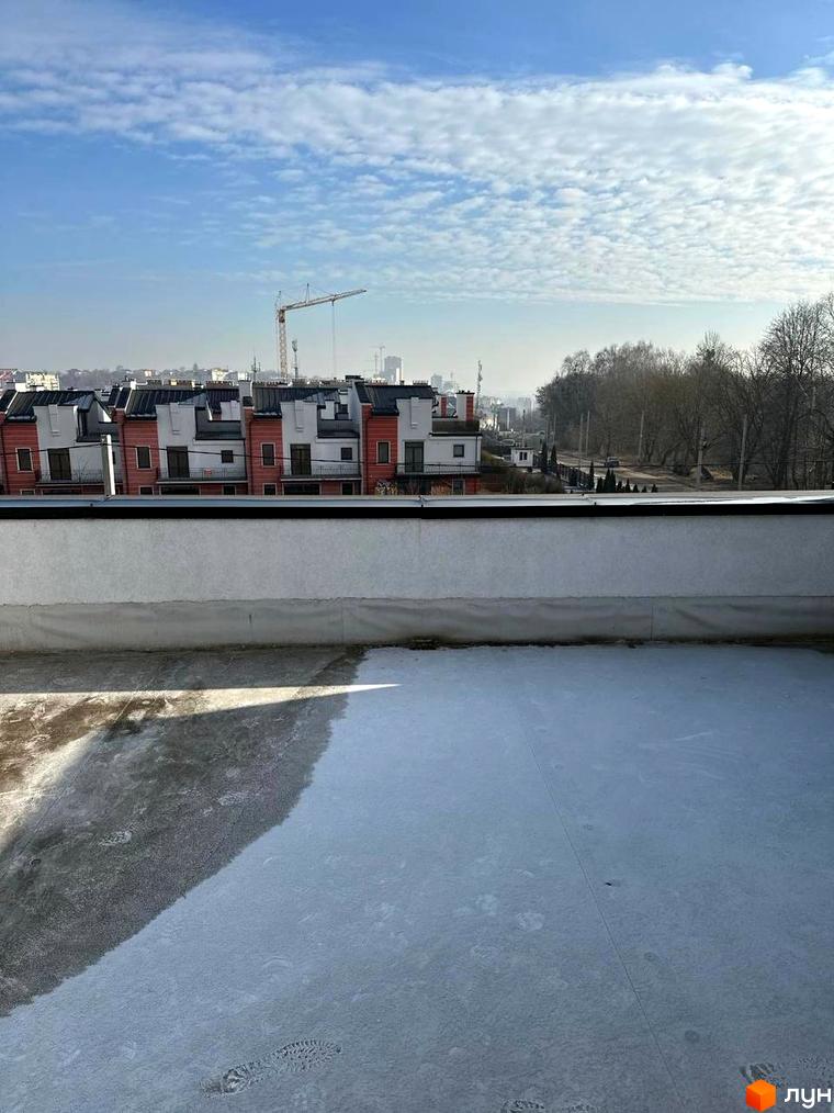 Вид на житловий комплекс на вулиці Пилипа Орлика, 51, з сучасними фасадами будинків та будівельними кранами на фоні. Тераса з покриттям та слідами від взуття.