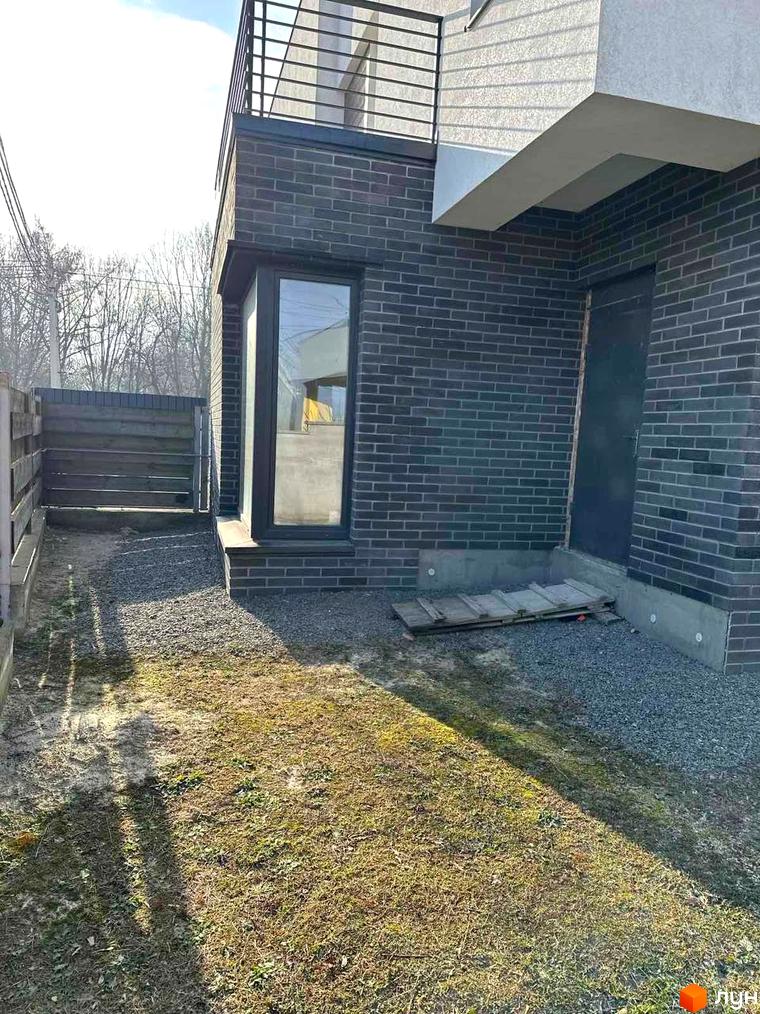 Зовнішній вигляд будинку з темної цегли та вікнами, прибудинкова територія з газоном та гравієм на вулиці Пилипа Орлика, 51.