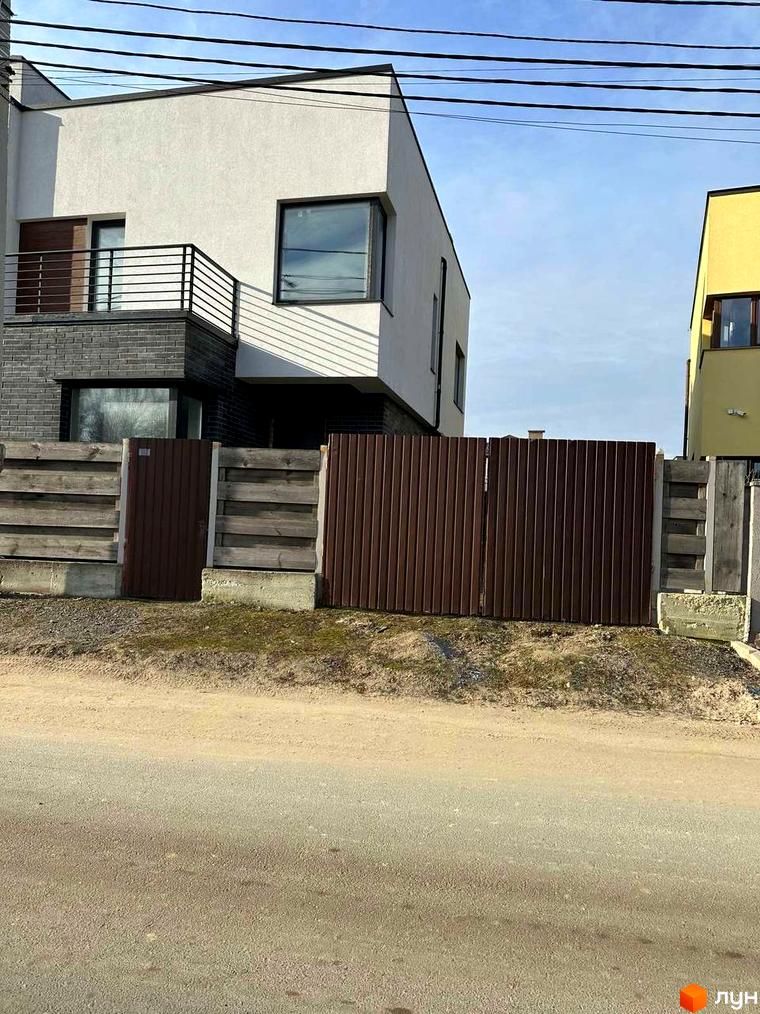 Сучасний житловий комплекс на вулиці Пилипа Орлика, 51, з металевим парканом та бетонними елементами. Навколо будинку розташована зелена зона та дорога.