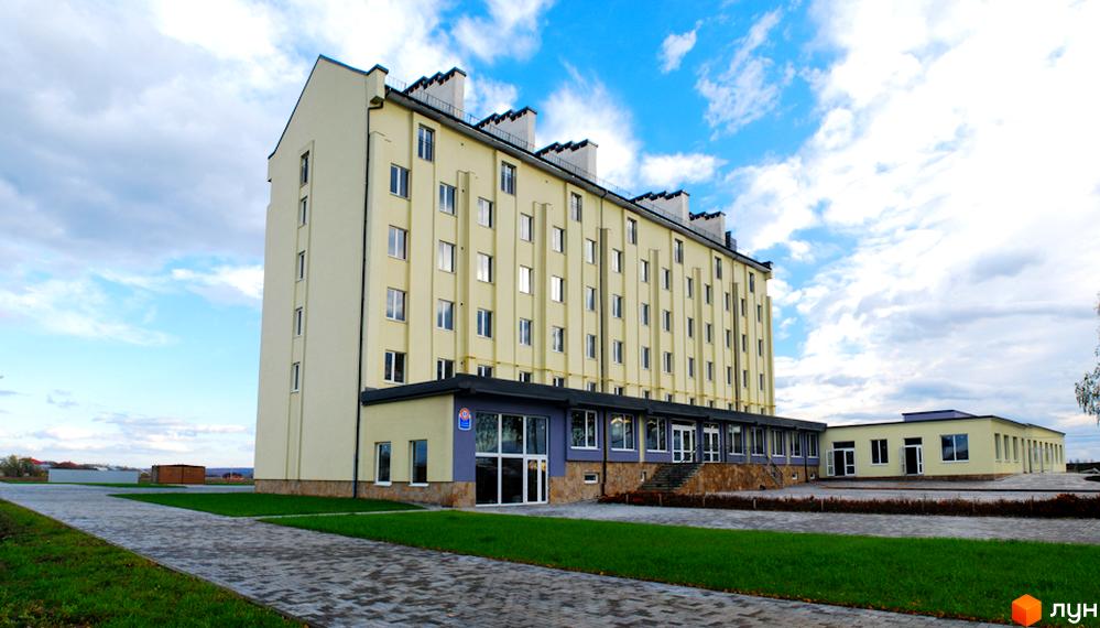 Зовнішній вигляд Житлового комплексу Сонячний. Багатоповерхова будівля з великою кількістю вікон та прибудинковою територією з тротуаром та газоном.