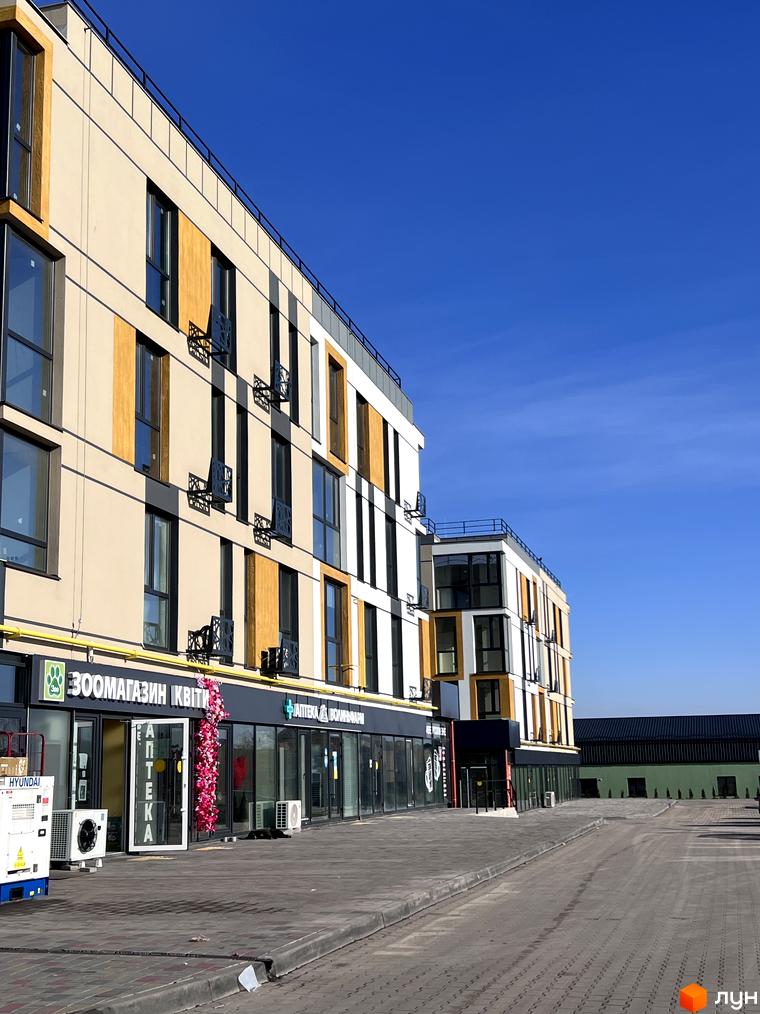 Зображення фасаду будинку в Житловому комплексі U HOME з магазинами на першому поверсі. Вигляд на прибудинкову територію.