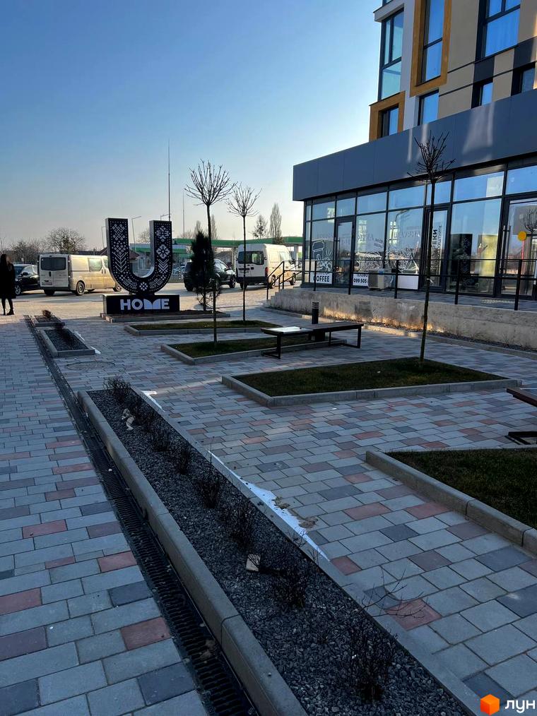 Зовнішній вигляд Новобудови U HOME та прибудинкової території. Викладена тротуарна плитка, встановлені лавки та висаджені дерева.