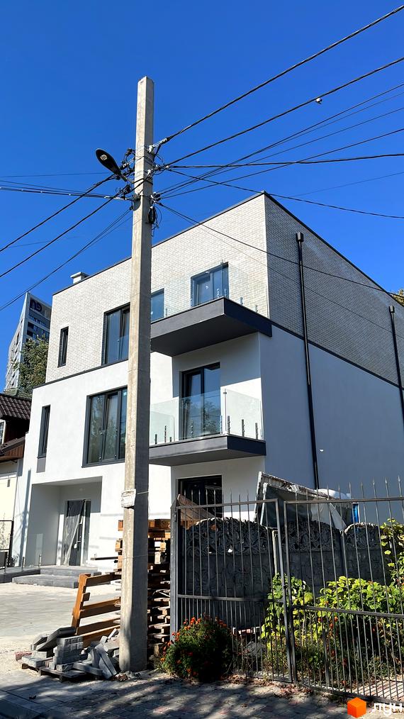 Новобудова на вулиці Вербова, 50 з сірою цегляною та білою штукатуркою, скляними балконами та прибудинковою територією з огорожею.