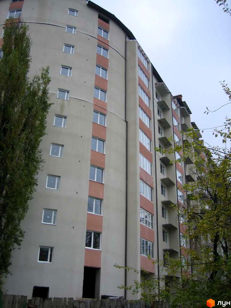 Зображення фасаду багатоповерхового будинку на вулиці Коновальця, 124. Житловий комплекс з балконами та великими вікнами.