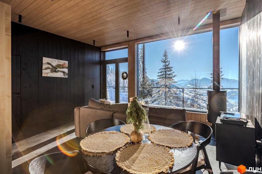 Інтер'єр вітальні з панорамним вікном, що виходить на гірський пейзаж, та обідньою зоною з круглим столом. КМ Висота 890 – ваш затишок серед гір.