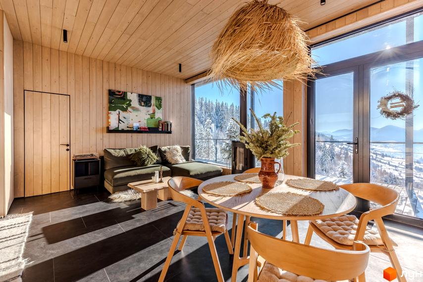 КМ Висота 890: затишна вітальня з панорамними вікнами та видом на зимовий ліс. Інтер'єр оформлений у стилі еко з дерев'яними елементами.