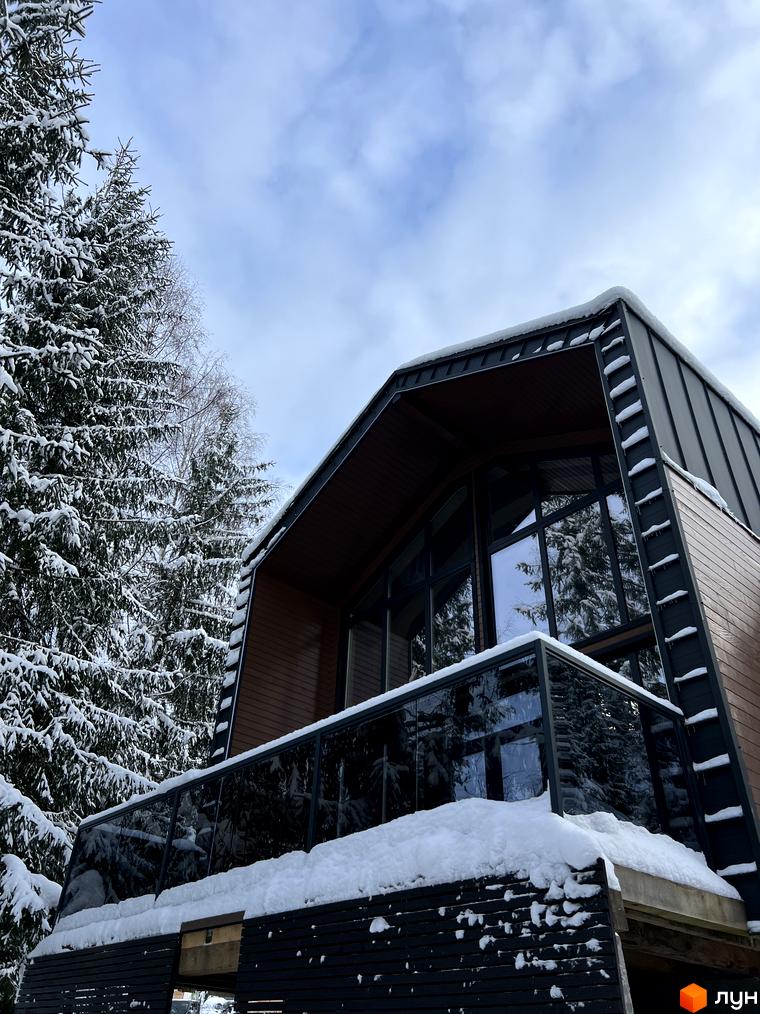 Котеджне містечко GORDO RESIDENCE: сучасний будинок з панорамними вікнами та скляним балконом, оточений засніженими ялинами.