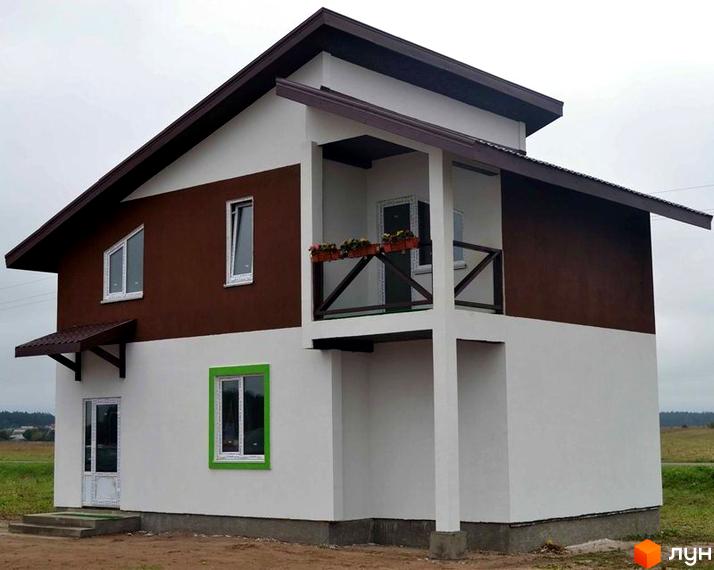 Зображення двоповерхового будинку в Котеджному містечку Святополе з балконом та зеленим газоном. Фасад будинку комбінований, білий та коричневий.