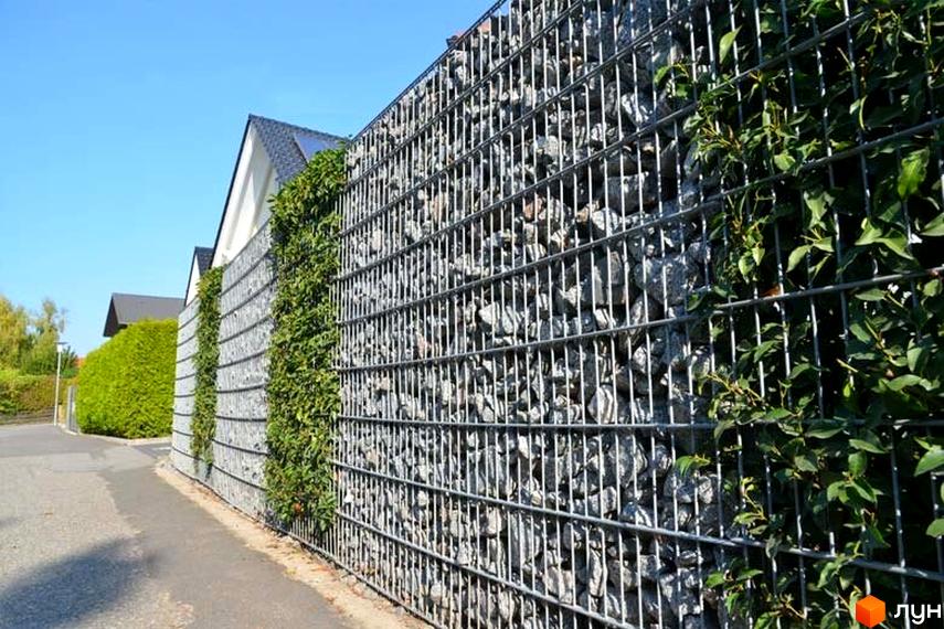 Таунхауси HILL HOUSE з кам'яним парканом та зеленню. Навколо будівель облаштована прибудинкова територія з доглянутими кущами та доріжками.