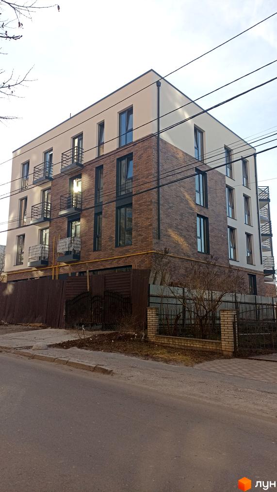 Зовнішній вигляд новобудови на вулиці Омеляна Польового, 3, з цегляним фасадом та балконами. Прибудинкова територія з огорожею та деревами.