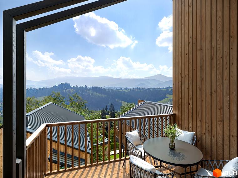 Вид з балкону на гори та котеджі житлового комплексу VERHGORY. Дерев'яна тераса з меблями для відпочинку.