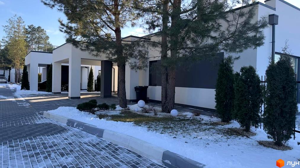 Котеджне містечко КМ Forest Villa з білими стінами та темними вікнами, оточене деревами та засніженою територією.