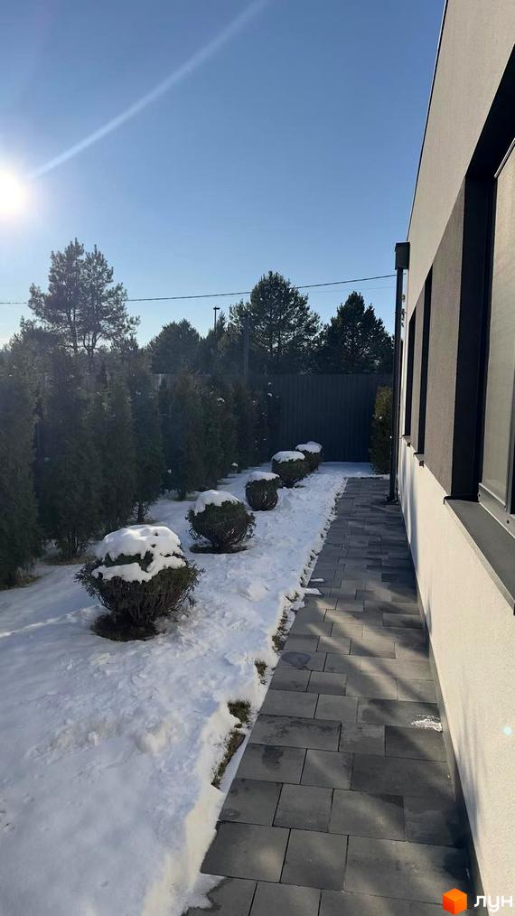 Котеджне містечко Forest Villa з сірим фасадом та доріжкою з плитки, оточене деревами та засніженою територією.
