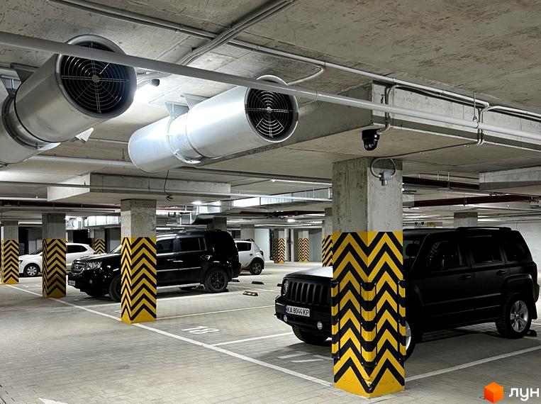 Підземний паркінг ЖК Park Residence з вентиляційними системами та паркувальними місцями. На стовпах нанесено попереджувальне маркування.