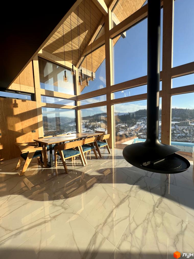 Інтер'єр будинку в Котеджному містечку Шале Вище Неба з панорамними вікнами, каміном та видом на гори. Світлий дизайн з дерев'яними елементами та мармуровою підлогою.