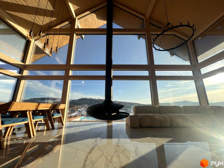 Будівля Котеджного містечка Шале Вище Неба має великі панорамні вікна та дерев'яні конструкції, з яких відкривається вид на зимові гори.