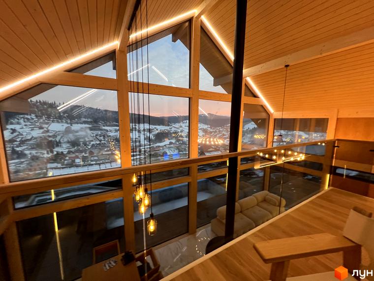Інтер'єр будинку в Містечку котеджів Шале Вище Неба з панорамними вікнами та видом на засніжені гори. Дерев'яне оздоблення створює атмосферу затишку.