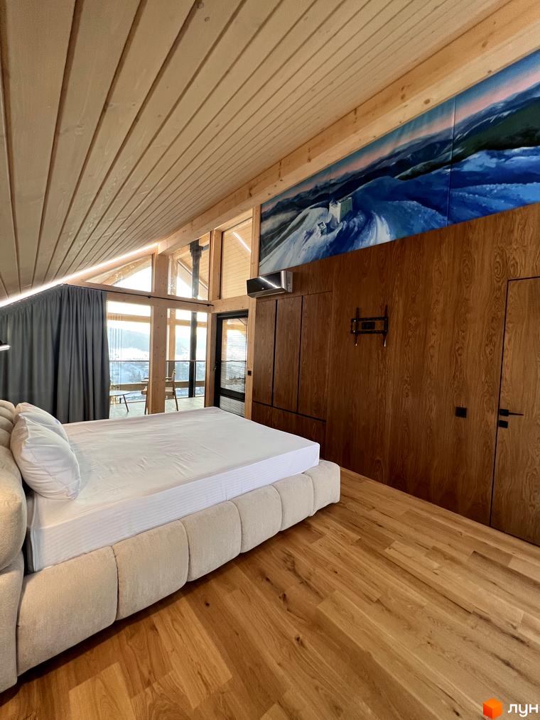 Інтер'єр спальні Котеджного містечка Шале Вище Неба: дерев'яні стіни та стеля, велике ліжко, панорамні вікна з видом на гори.