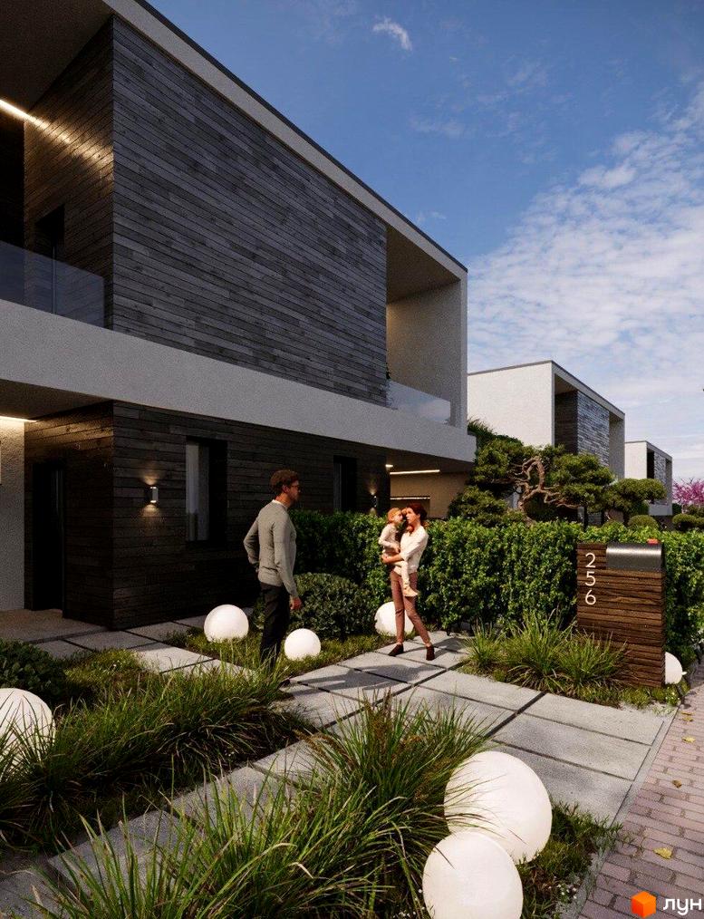 Фасад будинку з дерев'яним оздобленням. Біля будинку доглянутий газон з декоративними кулями та доріжками з плитки, зелені насадження.