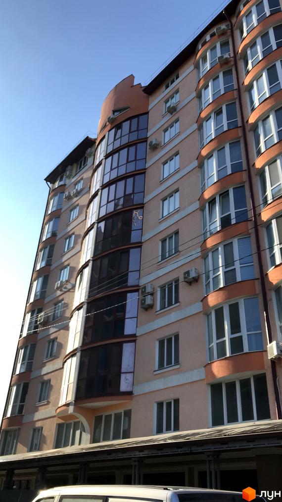 Фасад новобудови Героїв Майдану, 53 з вигнутими балконами та панорамними вікнами. Будинок має персиковий колір стін та оранжеві елементи оздоблення.